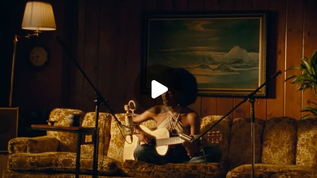 A musician performs on a couch in a warmly lit room for SIGNAL.