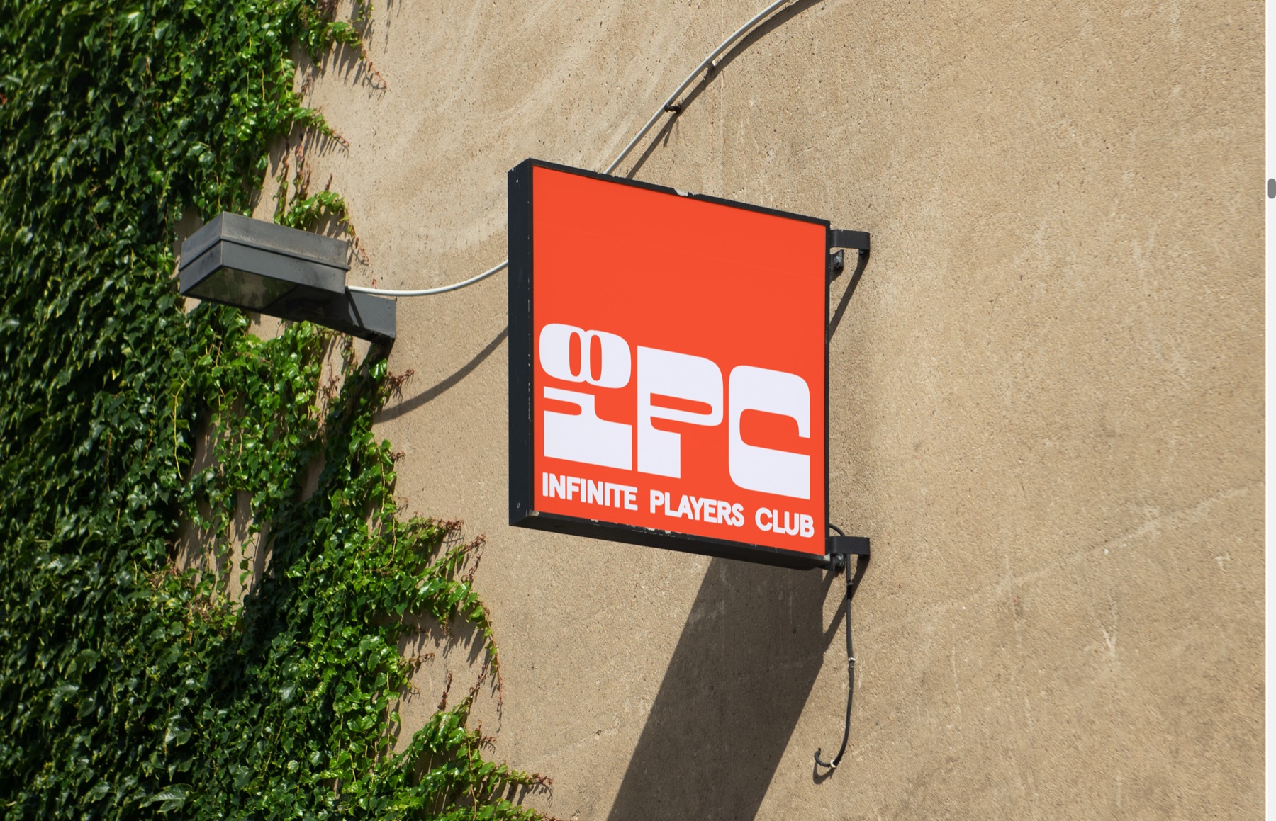 An Infinite Players Club sign mounted on a sunlit wall beside climbing ivy.