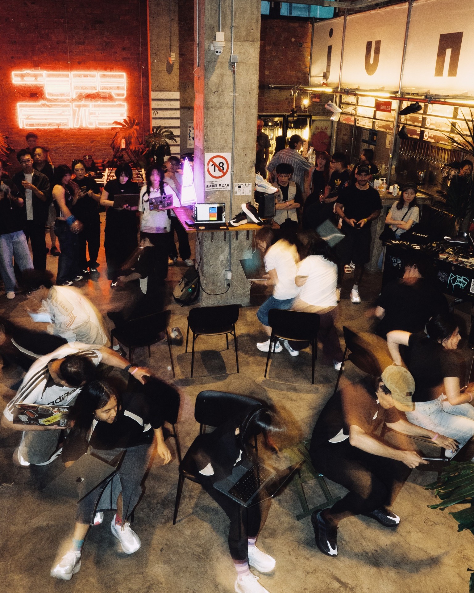 People carrying laptops circle chairs during a collective vibe-coding game in Shanghai.